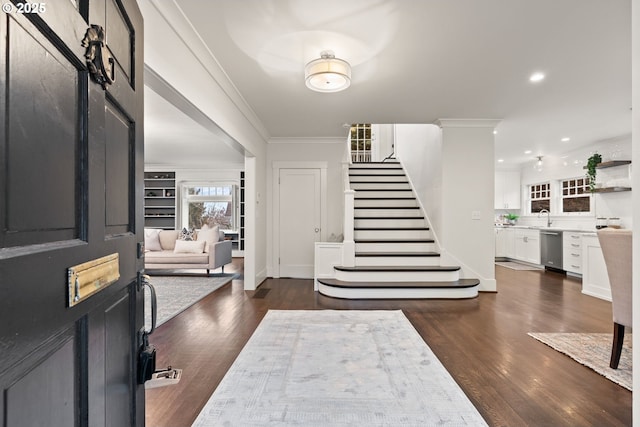 foyer entrance with ornamental molding, dark hardwood / wood-style flooring, and sink