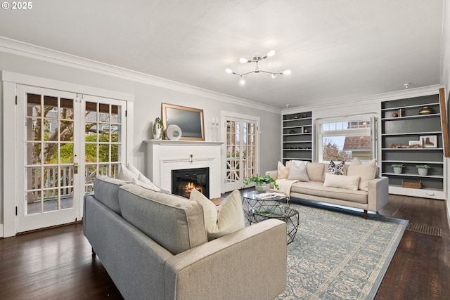 living room with dark hardwood / wood-style flooring, built in features, ornamental molding, and french doors