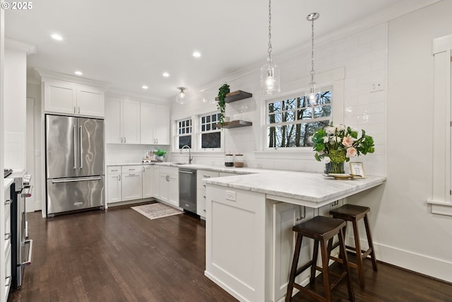 kitchen featuring white cabinetry, stainless steel appliances, a breakfast bar area, and light stone counters