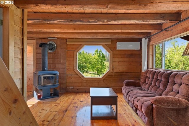 35912 Valley View Ln, Halfway, OR 97834 - living room featuring wooden walls, light wood finished floors, a wall mounted air conditioner, a wood stove, and wood ceiling with exposed beams