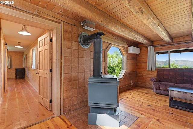 35912 Valley View Ln, Halfway, OR 97834 - living area featuring light wood finished floors, wood walls, a wood stove, wooden ceiling with exposed beams, and a wall unit AC