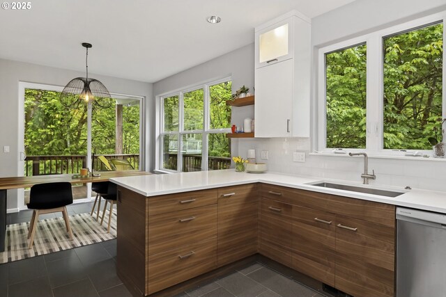 kitchen with white cabinets, light countertops, a sink, and dishwasher