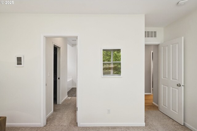 interior space with visible vents, baseboards, and light colored carpet