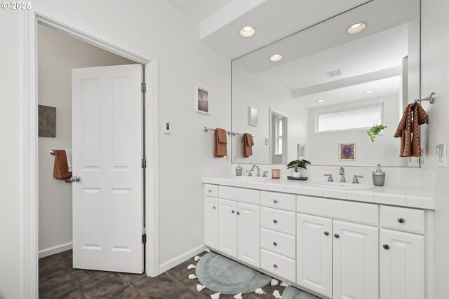 bathroom featuring double vanity, baseboards, and a sink