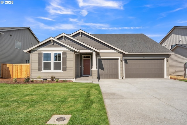 craftsman-style home featuring roof with shingles, concrete driveway, fence, a garage, and a front lawn