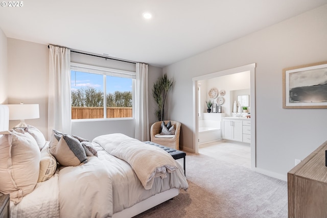 bedroom featuring baseboards, ensuite bathroom, and light colored carpet