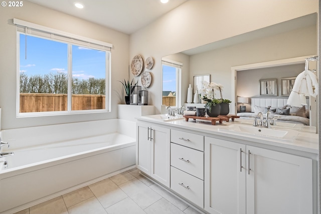 ensuite bathroom featuring double vanity, a sink, a bath, and tile patterned floors