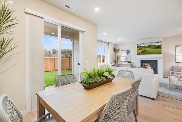 dining room featuring recessed lighting, visible vents, light wood-style flooring, a glass covered fireplace, and baseboards