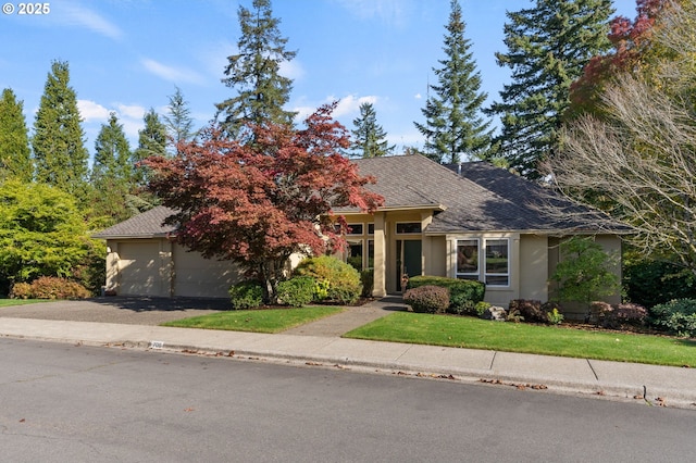 view of front of house with roof with shingles, stucco siding, a front lawn, and aphalt driveway