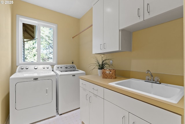 clothes washing area featuring a sink, light floors, cabinet space, and washing machine and clothes dryer