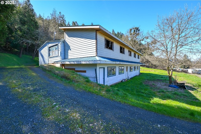 view of side of property featuring metal roof and a lawn