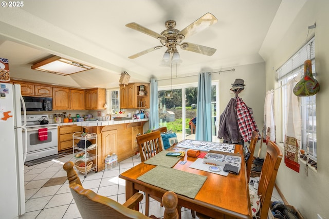 dining space with vaulted ceiling, light tile patterned floors, and a ceiling fan