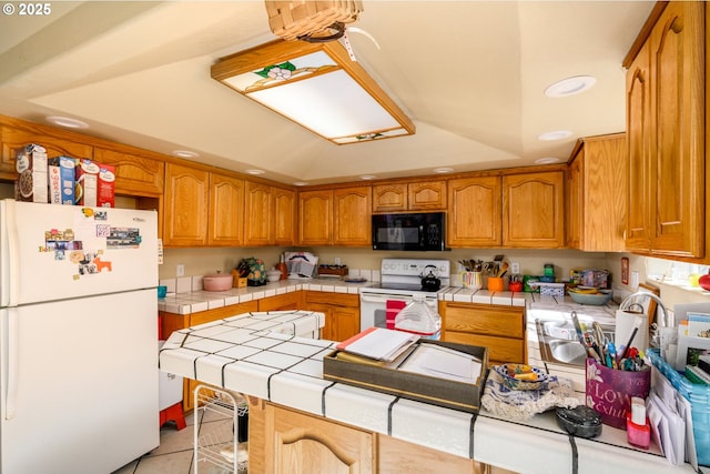 kitchen with brown cabinets, a tray ceiling, tile countertops, white appliances, and light tile patterned floors