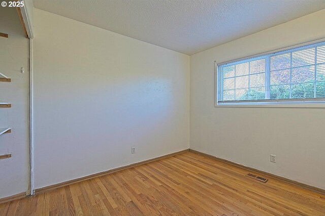 unfurnished room featuring baseboards, light wood-type flooring, and visible vents