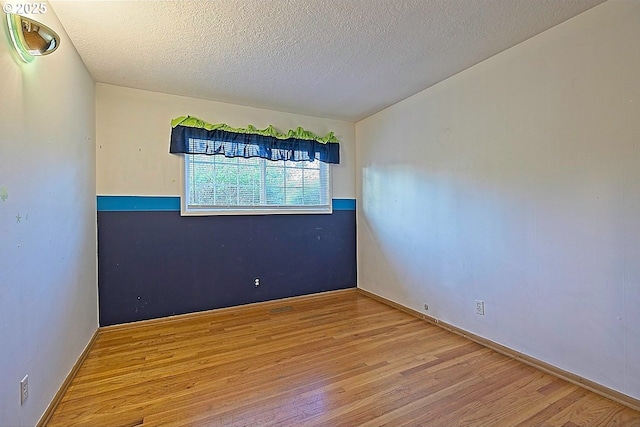 unfurnished room with a textured ceiling and wood finished floors
