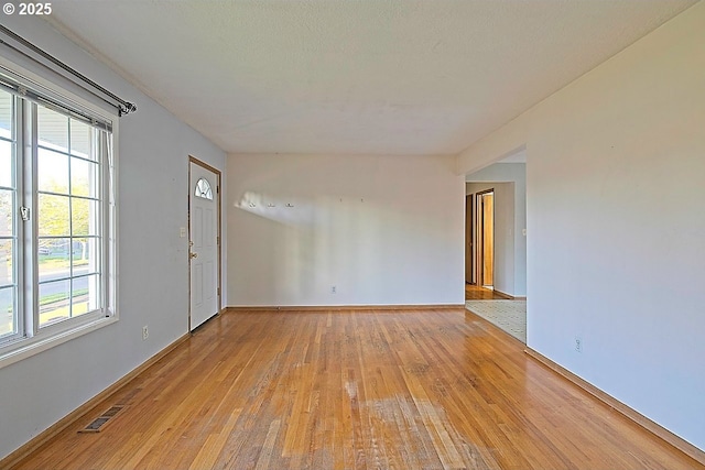 spare room with baseboards, visible vents, a healthy amount of sunlight, and light wood-style flooring