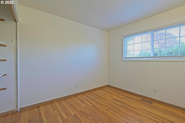unfurnished room featuring baseboards, light wood-type flooring, and visible vents