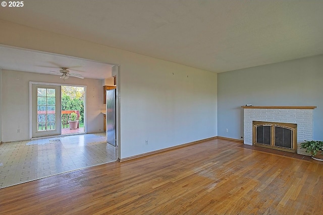 unfurnished living room with baseboards, ceiling fan, a fireplace, and wood finished floors