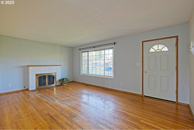 unfurnished living room with light wood-style floors, baseboards, and a fireplace