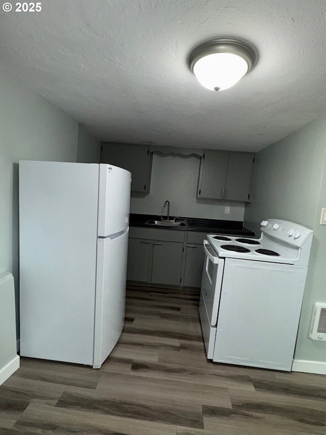 1605 4th St, Salem, OR 97301 - kitchen with white appliances, a sink, dark countertops, dark wood-style floors, and a textured ceiling