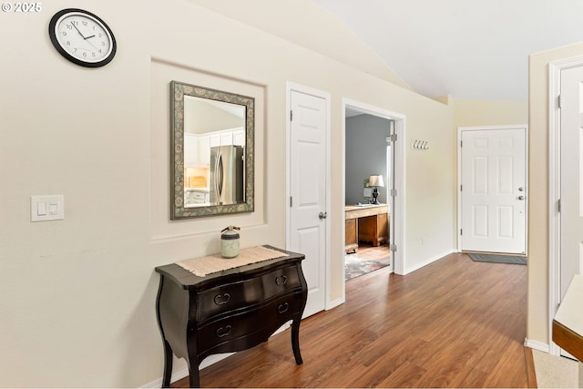 hall with lofted ceiling, wood finished floors, and baseboards