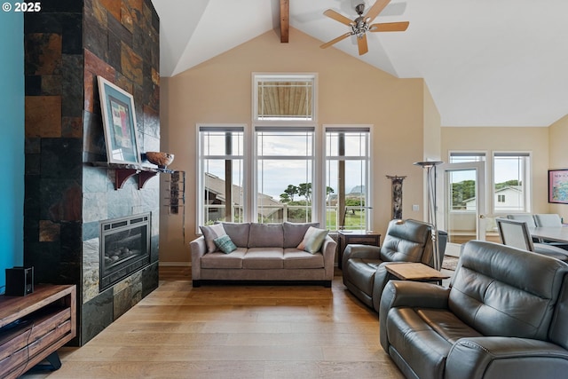 living room with ceiling fan, beam ceiling, wood-type flooring, high vaulted ceiling, and a fireplace