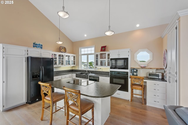 kitchen featuring white cabinetry, hanging light fixtures, a center island, and black appliances