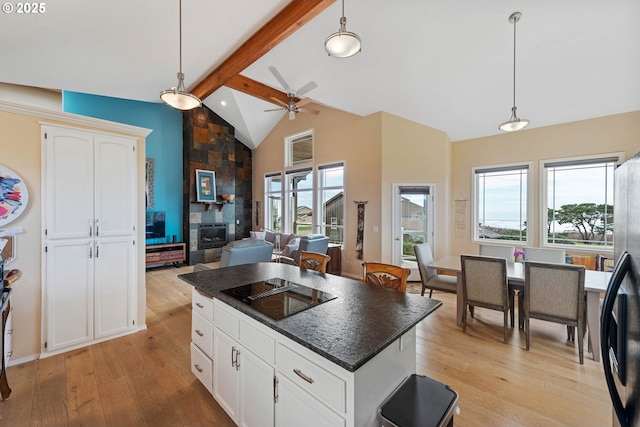 kitchen featuring black electric stovetop, decorative light fixtures, lofted ceiling with beams, and white cabinetry