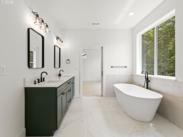 6715 NE 132nd St, Vancouver, WA 98686 - bathroom featuring healthy amount of natural light, double vanity, a freestanding bath, marble tiled flooring, and tile walls