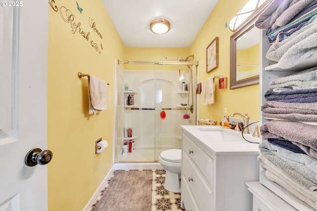 bathroom with a stall shower, baseboards, vanity, and toilet