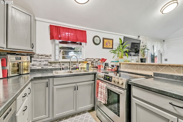 kitchen with stainless steel electric range oven, backsplash, dark countertops, and a sink