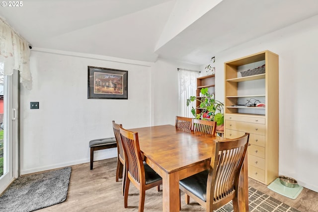 dining room featuring lofted ceiling, light wood-style flooring, and built in features