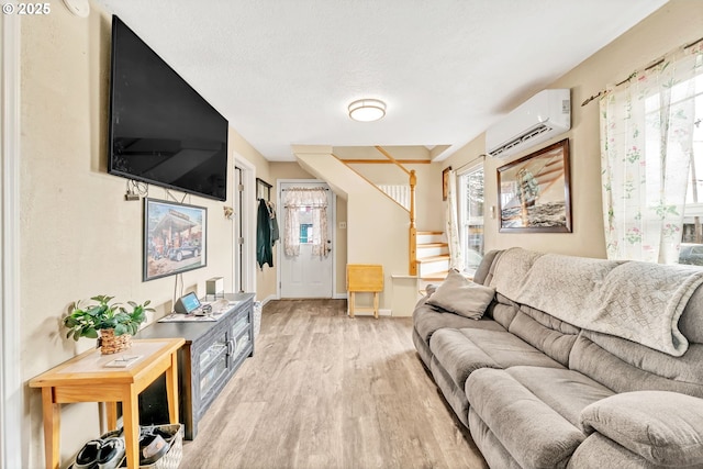 living room with baseboards, light wood-style flooring, stairs, a textured ceiling, and an AC wall unit