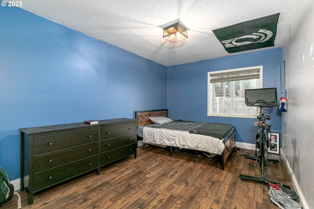 bedroom with a textured ceiling, baseboards, and wood finished floors