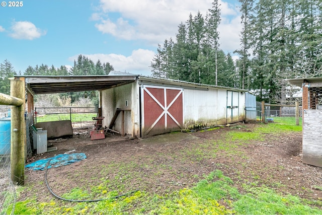 view of outbuilding featuring a carport, an outbuilding, and fence