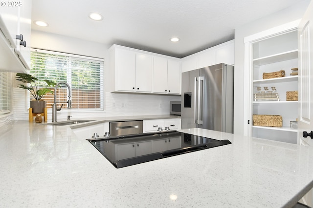 18294 SW Bergs Ct, Beaverton, OR 97003 - kitchen featuring appliances with stainless steel finishes, a sink, white cabinetry, decorative backsplash, and light stone countertops