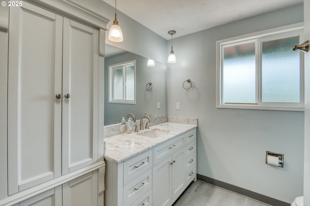 bathroom featuring healthy amount of natural light, vanity, wood finished floors, and baseboards