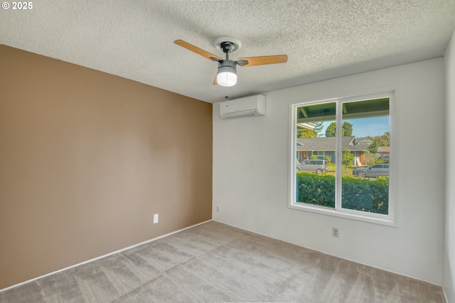 empty room with a wall mounted air conditioner, ceiling fan, light carpet, and a textured ceiling
