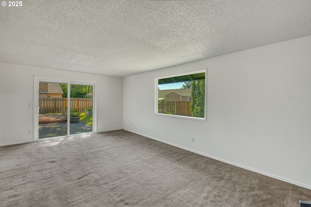 spare room featuring a textured ceiling, carpet floors, and baseboards