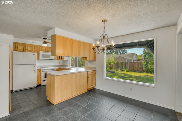 kitchen featuring white appliances, a peninsula, light countertops, plenty of natural light, and a textured ceiling