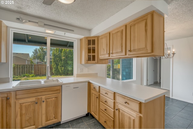 kitchen with white dishwasher, a sink, a textured ceiling, a peninsula, and light countertops