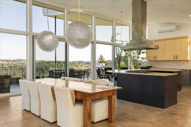 interior space featuring light brown cabinets, a high ceiling, an AC wall unit, a center island, and island exhaust hood