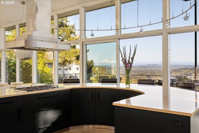 1900 Crest Dr, Lake Oswego, OR 97034 - kitchen featuring dark cabinetry, wall chimney range hood, stainless steel gas cooktop, light countertops, and a mountain view