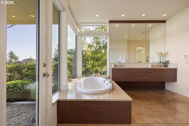 bathroom with vanity, recessed lighting, finished concrete floors, tasteful backsplash, and a garden tub