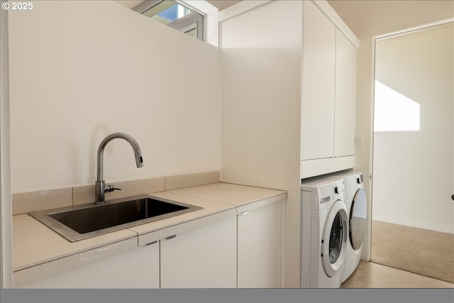 laundry area with cabinet space, independent washer and dryer, and a sink