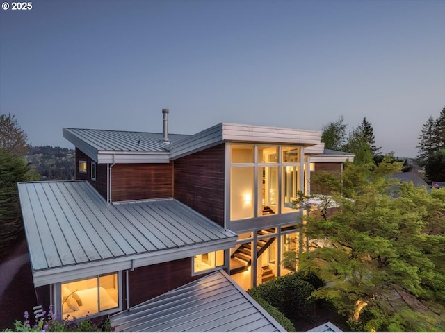 back of property with a standing seam roof, a sunroom, and metal roof