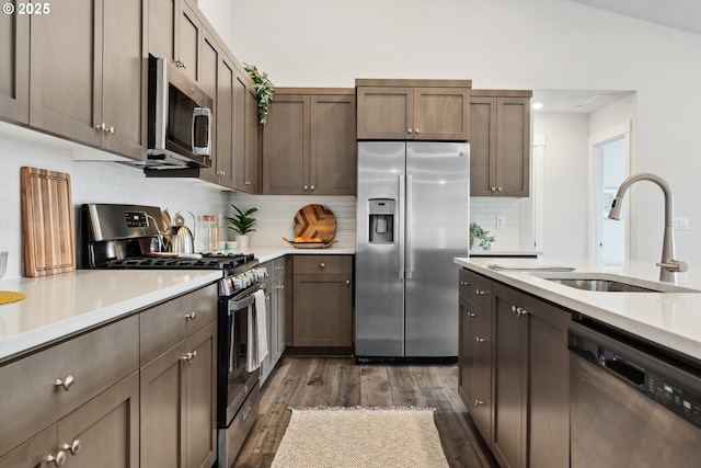 kitchen with dark wood-style flooring, stainless steel appliances, light countertops, and a sink