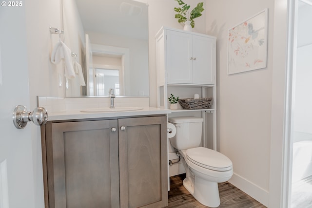 bathroom with wood finished floors, toilet, vanity, and baseboards