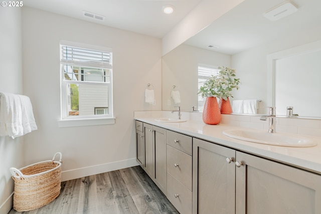 bathroom with double vanity, a sink, wood finished floors, and visible vents
