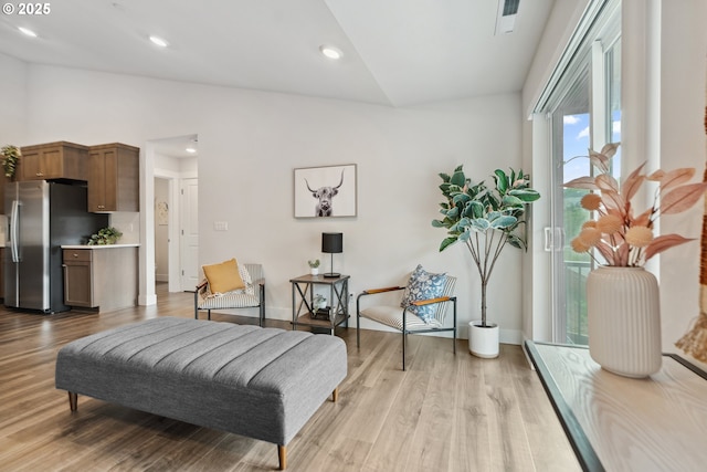 sitting room featuring lofted ceiling, visible vents, light wood finished floors, and baseboards
